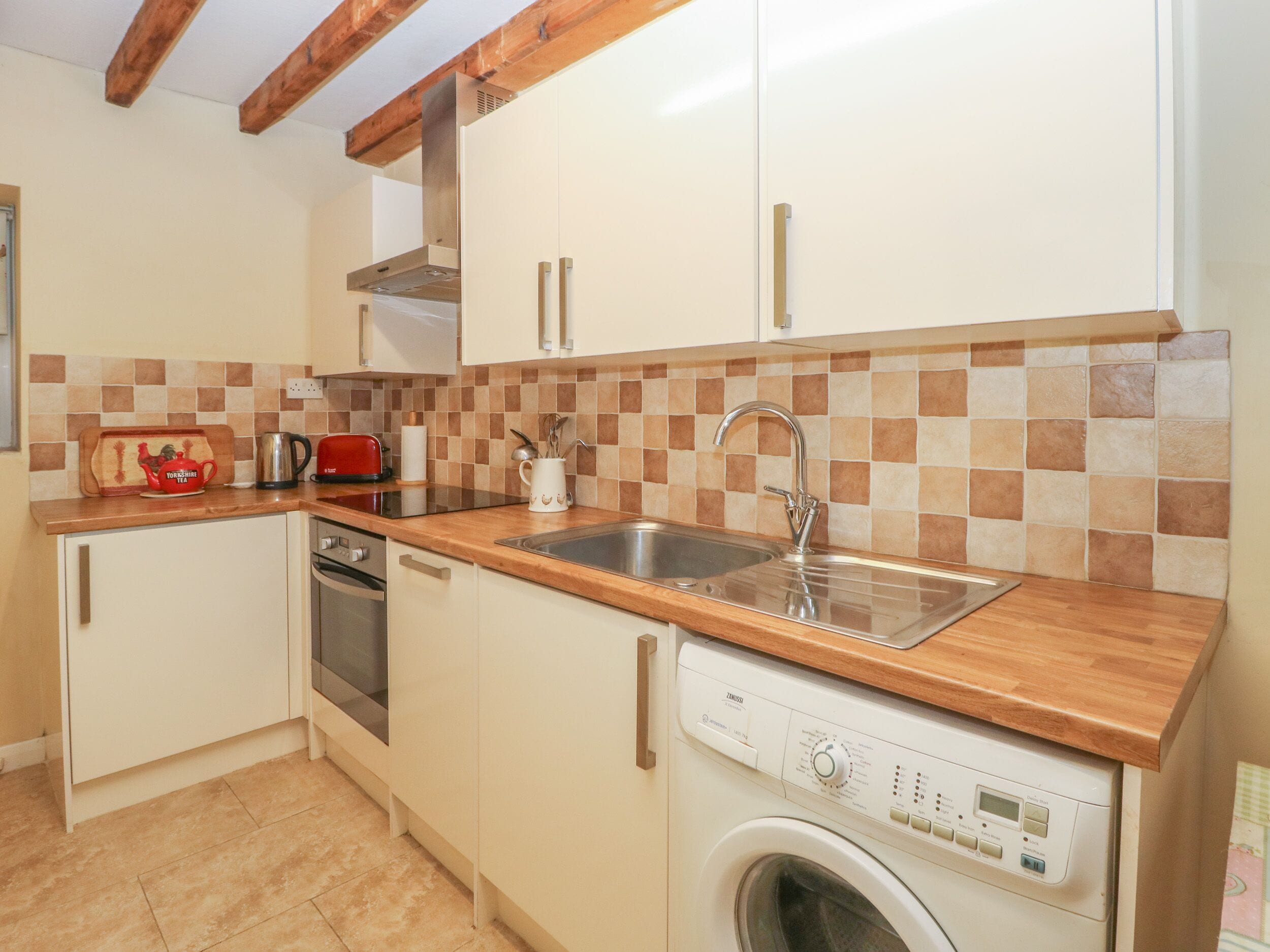 Een praktische keuken met een vaatwasser, een wasmachine en een spoelbak.