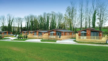 Eine Reihe von Holzhütten mit Balkonen, gelegen in einer grünen Wiese mit Bäumen im Hintergrund.