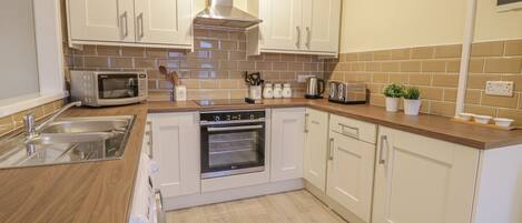 A modern kitchen with white cabinets, a stainless steel range hood, a microwave, a toaster, and a dishwasher.