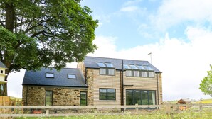 A modern two-story house with stone and wood exterior, large windows, and a fenced yard. - Briar Barn (Bishop Auckland)