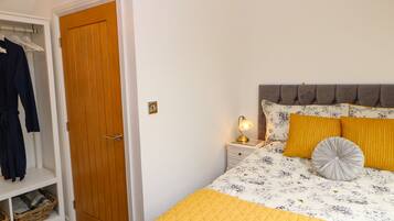 Un dormitorio con cama, mesita de noche, armario y puerta.