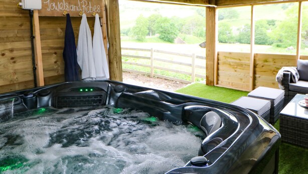 A wooden spa room with a hot tub, towels, and a view of the outdoors. - Briar Barn (Bishop Auckland)