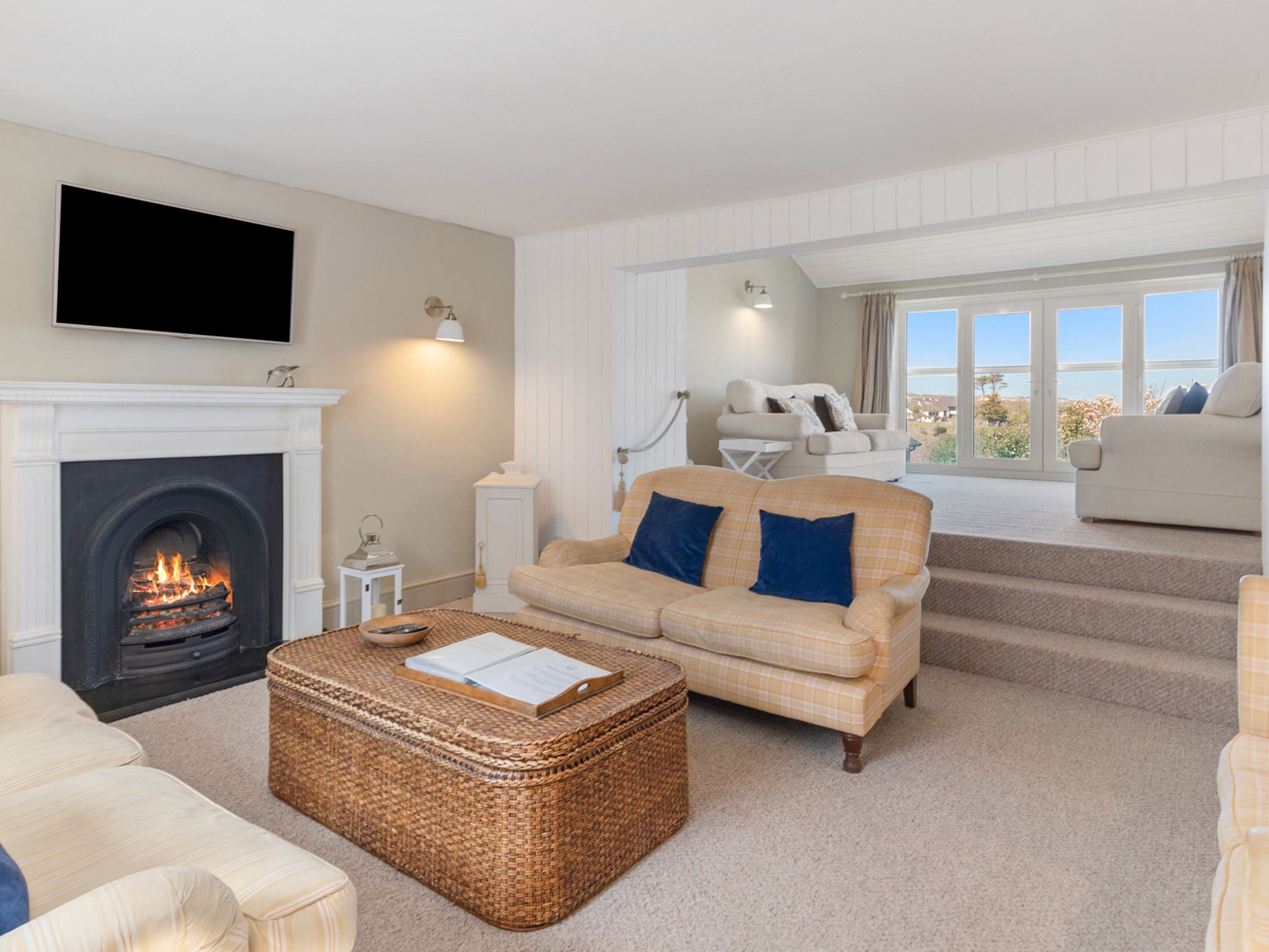 A living room with a fireplace, a sofa, a coffee table, and a television mounted on the wall.