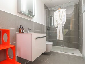 A modern bathroom with a glass shower enclosure, a white vanity, and a red accent piece. - Idlewild, 2 Wheal Turnavore (St. Agnes)