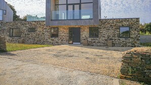 A modern two-story house with a stone facade, large windows, and a wooden roof. - Idlewild, 2 Wheal Turnavore (St. Agnes)