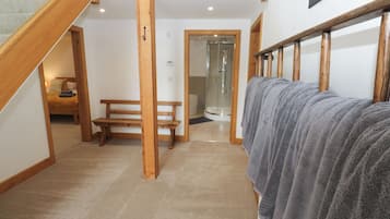 A hotel bathroom with a shower, a bench, and towels on a rack.