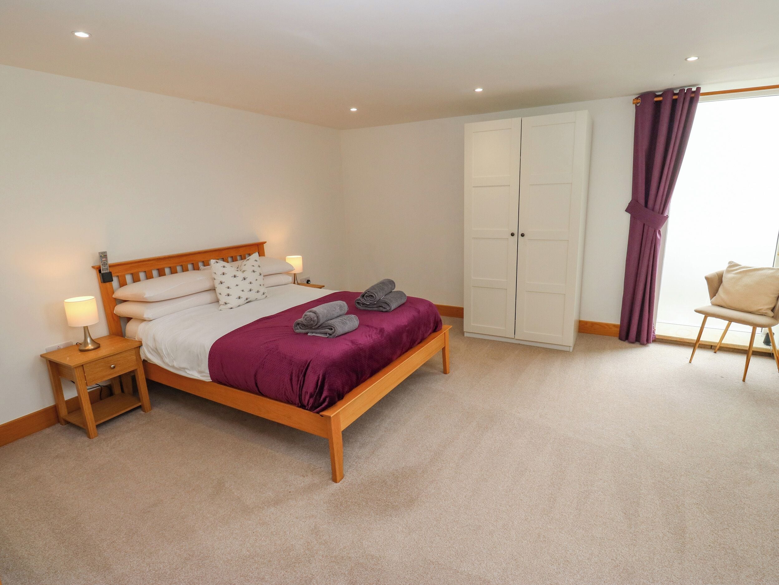 A bedroom with a bed, nightstands, a wardrobe, and a chair.
