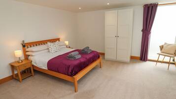 A bedroom with a bed, nightstands, a wardrobe, and a chair.