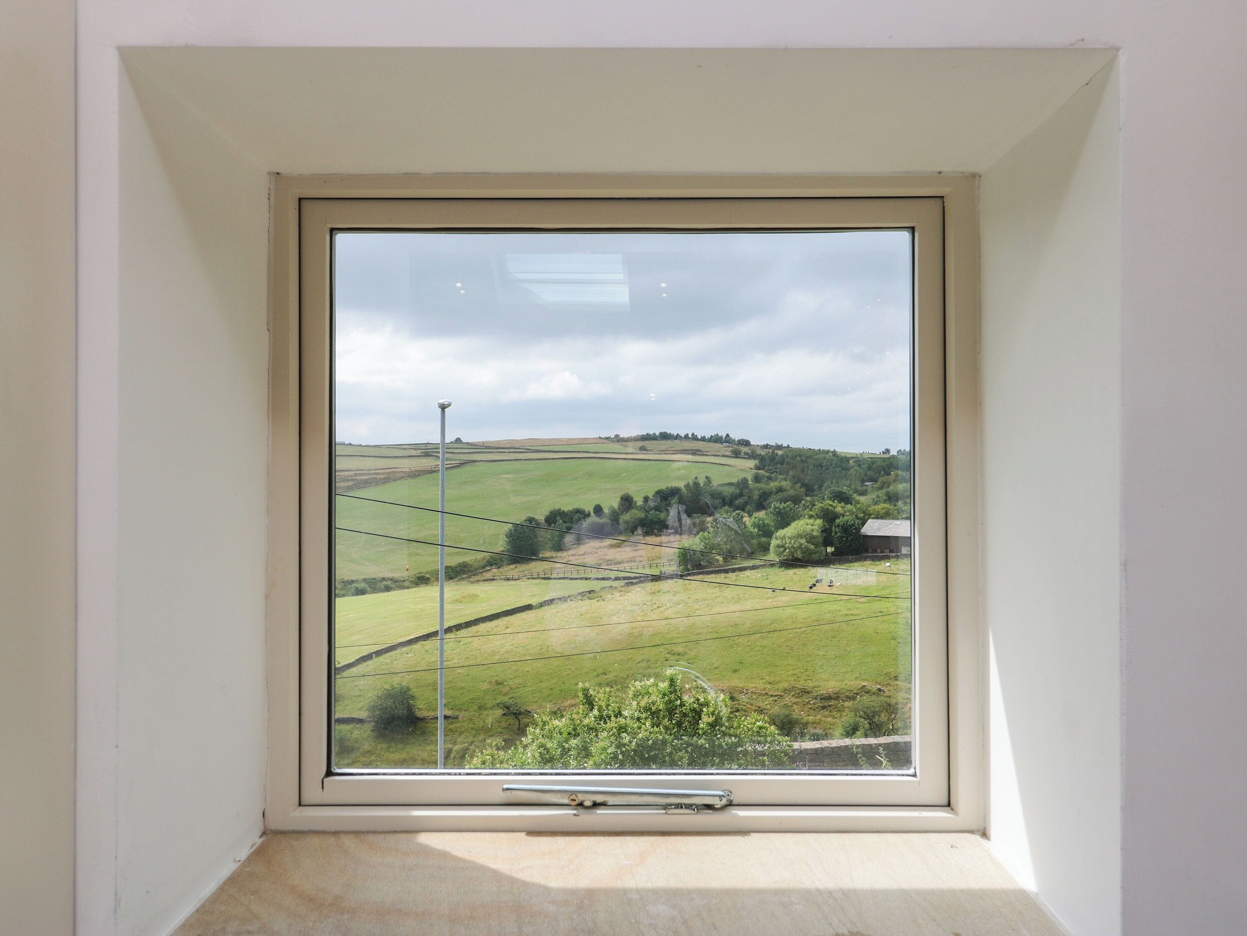 A room with a large window overlooking a rural landscape.