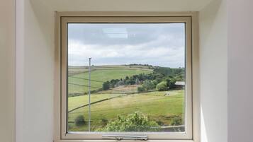 A room with a large window overlooking a rural landscape.