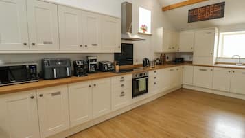 A kitchen with white cabinets, a wooden countertop, a coffee machine, and a sign indicating a coffee shop.