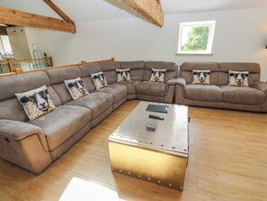 A living room with a sectional sofa, a coffee table, and a window with a view of trees.
