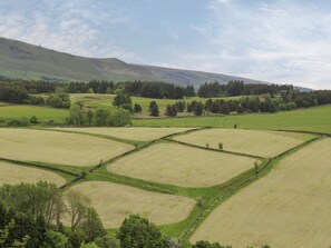 A rural landscape with terraced fields and a distant mountain range. - Upper House Barn (Oldham)