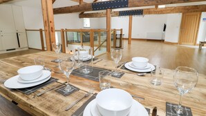 Un coin repas avec une table en bois mise pour le repas, comprenant des assiettes, des verres et des couverts.