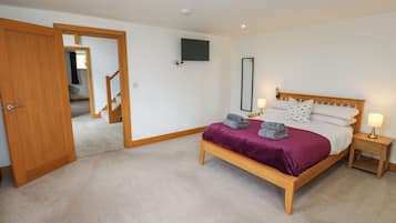 A bedroom with a wooden bed, a television on the wall, and a carpeted floor.