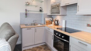 A compact kitchen with a sink, stove, microwave, and wooden countertop. - 3 Tidal (Rye)