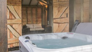 A hot tub in a wooden cabin with a sofa and a table. - Hillside Lodge (Ludlow)