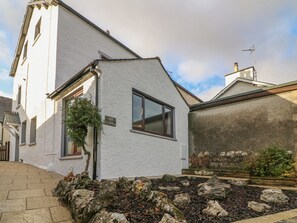 Un edificio bianco con un piccolo giardino, il numero '129' ben visibile e un camino.