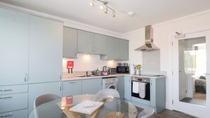A modern kitchen with light blue cabinets, a glass dining table, and a built-in oven. - The Nook (Inverness)