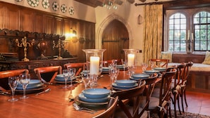 Een eetkamer met een lange houten tafel gedekt voor een maaltijd, omringd door houten stoelen.