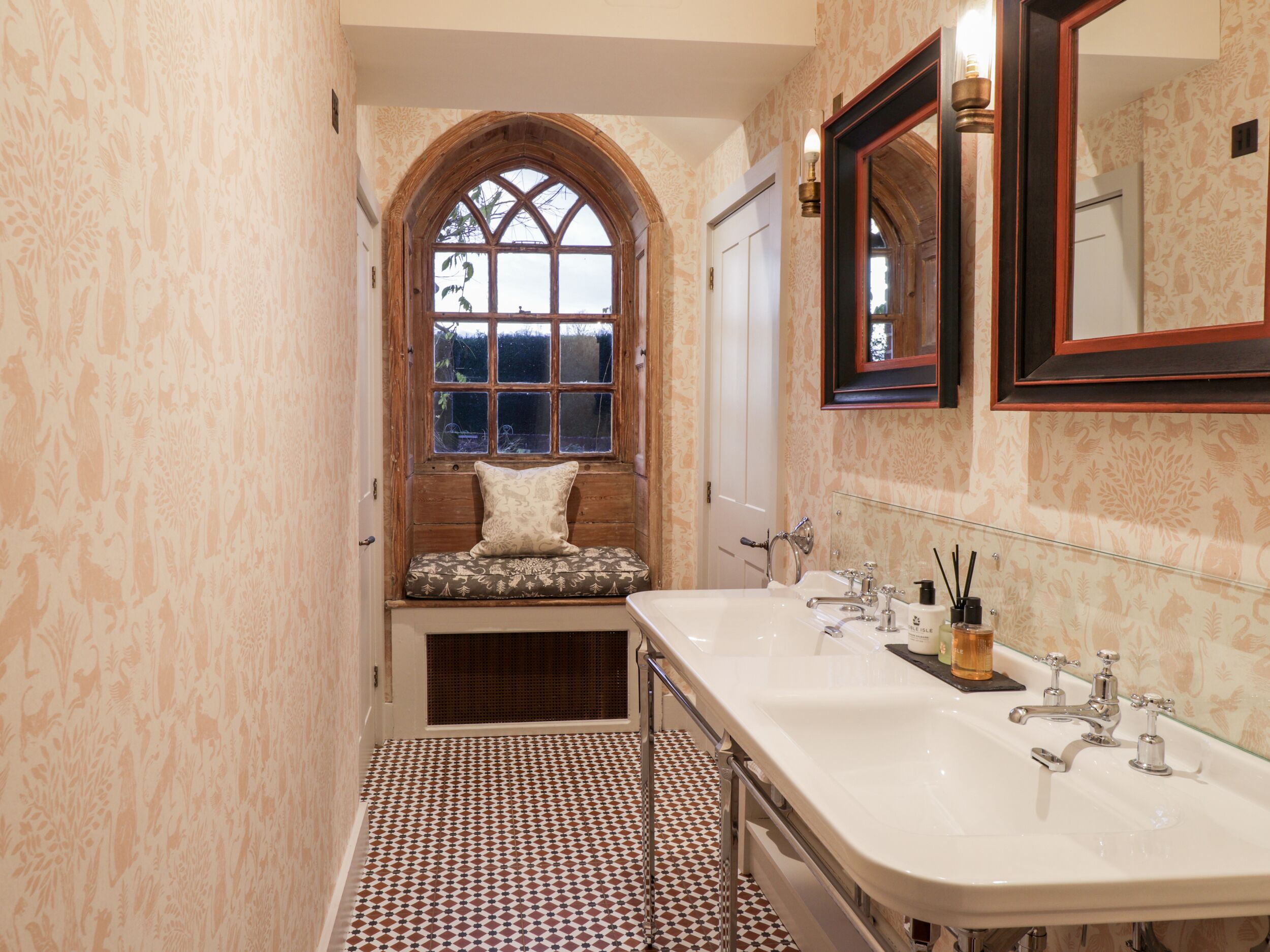 Un bagno con un'ampia finestra ad arco, una vasca e un lavabo doppio.