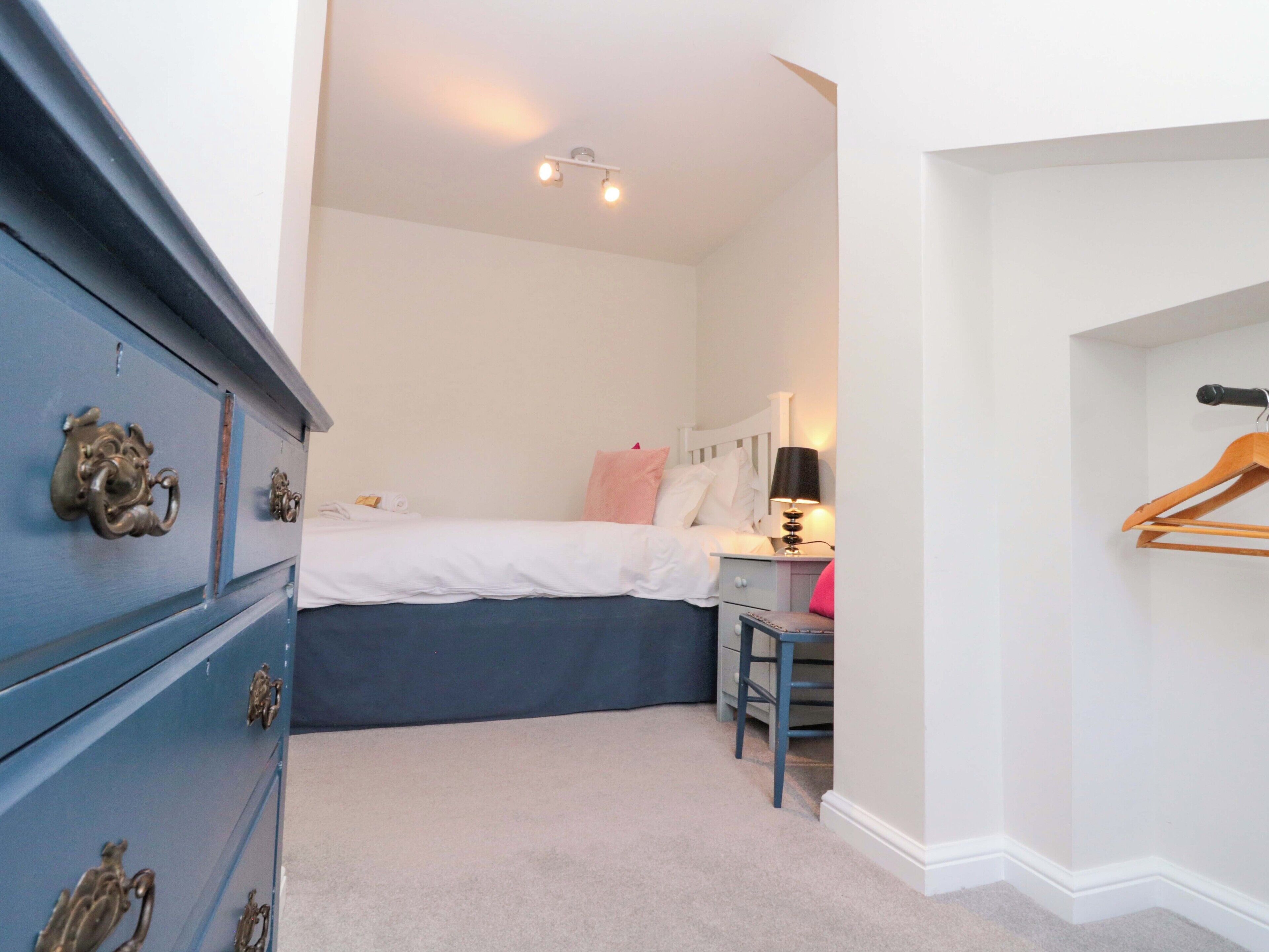 Une chambre à coucher comprenant un lit, une commode, un bureau et une tringle pour suspendre les vêtements dans un placard.