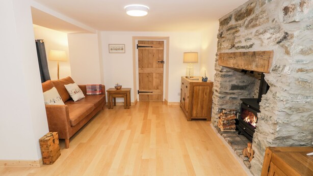Un salon chaleureux avec une cheminée en pierre, des meubles en bois et un plancher en bois.