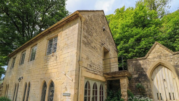 Ein Steinhaus mit Bogenfenstern und einer Tür, mit der Aufschrift "CHAPEL COTTAGE".