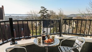 A balcony with a table, two chairs, a coffee pot, and a plate of croissants. - Cambrie (Tenby)
