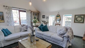 Ein Wohnzimmer mit zwei weißen Sofas, einem Holztisch und einem Bücherregal.