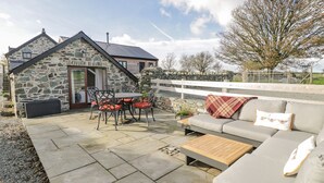Ein Steinhaus mit Terrasse, Sitzgelegenheit und Blick ins Grüne.