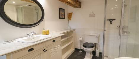 A bathroom with a marble sink, a toilet, a shower, and a large mirror.