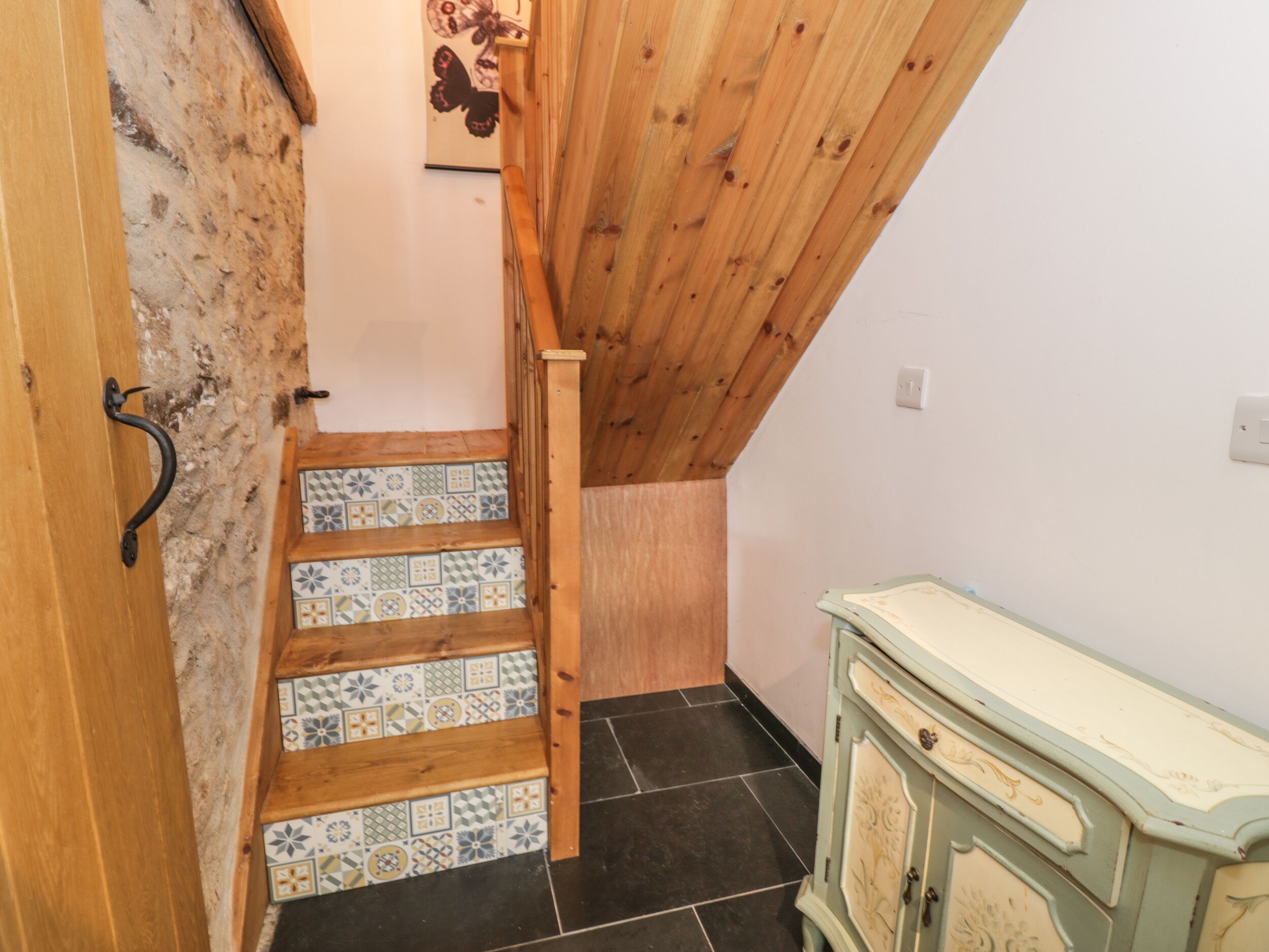 A staircase with patterned tiles leading to a wooden ceiling.