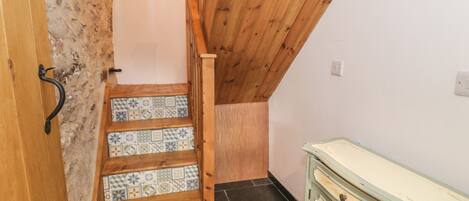 A staircase with patterned tiles leading to a wooden ceiling.