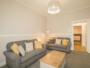 Ein Wohnzimmer mit zwei grauen Sofas, einem Holztisch und einer Chandelier.
