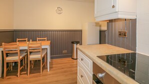 Una cocina compacta con una mesa y sillas, horno empotrado y un reloj en la pared.