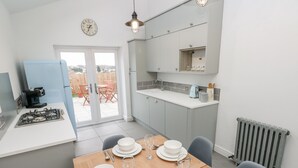 A modern kitchen with a gas stove, a coffee machine, and a dining area set for four with white plates, glasses, and cutlery.
