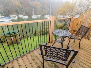 A balcony with a view of boats on a lake, a trash bin, and metal chairs. - Pearsall (Ambleside)