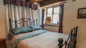 A bed with a metal frame, a window with curtains, and a painting on the wall.