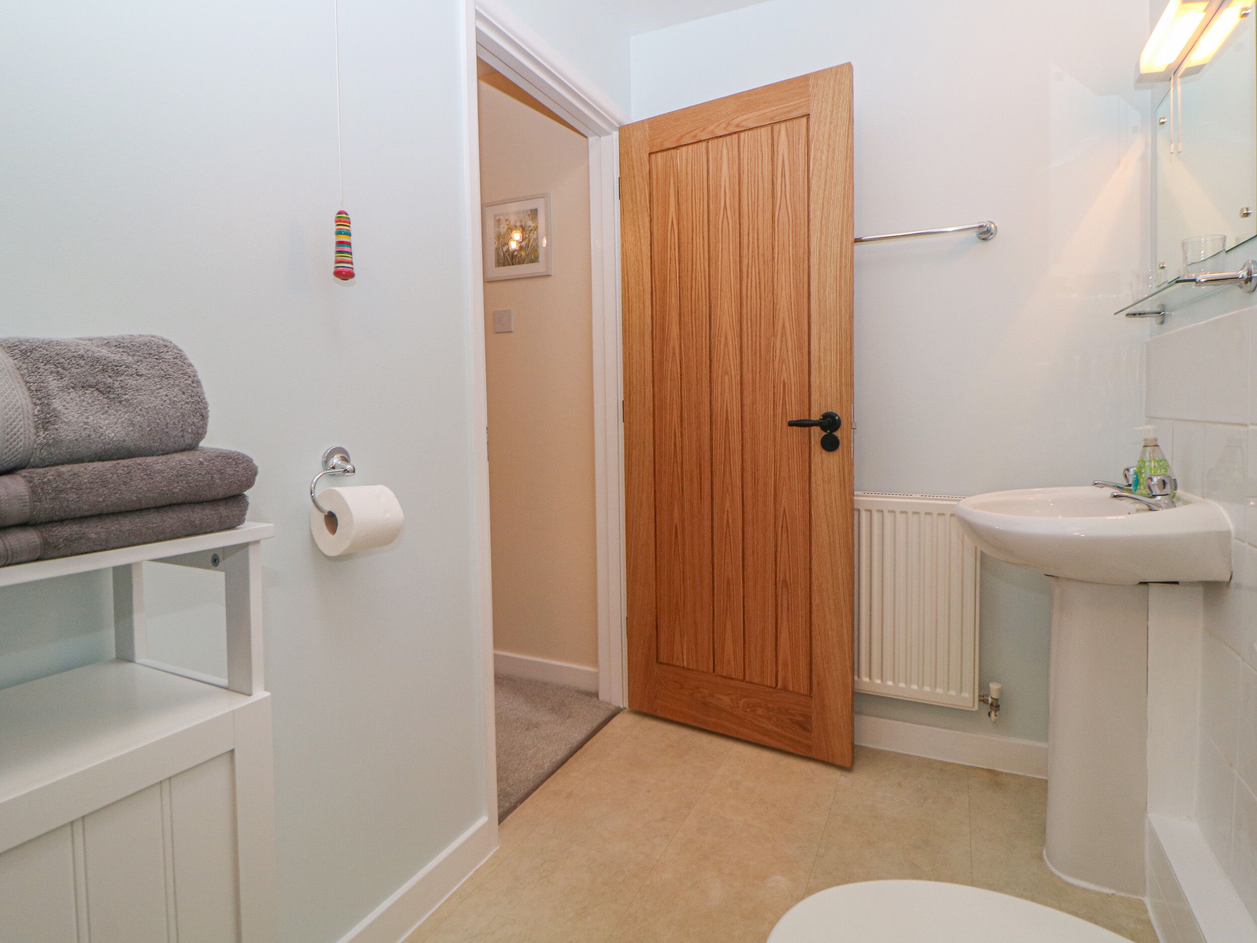 Une salle de bain avec une porte en bois, des toilettes, un lavabo et un porte-serviettes.