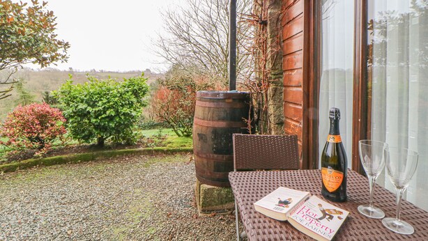 Une terrasse avec une table dressée pour deux personnes, une bouteille de vin et deux verres.