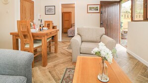 Un salon chaleureux comprenant un coin repas, un canapé et une table basse agrémentée d’un vase de fleurs.