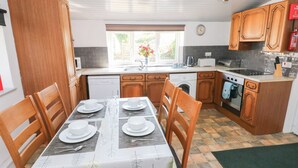 A compact kitchen with wooden cabinets, a dishwasher, a washing machine, and a stove.