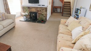 A cozy living room with a fireplace, a television, and a staircase leading to another level.