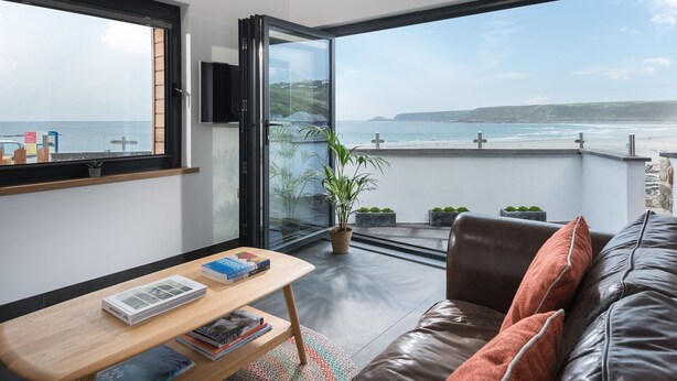 A modern living room with a large window overlooking a beach.
