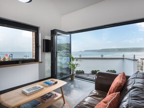 Un salon moderne doté d’une grande fenêtre donnant sur une plage.