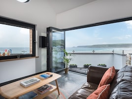 A modern living room with a large window overlooking a beach.