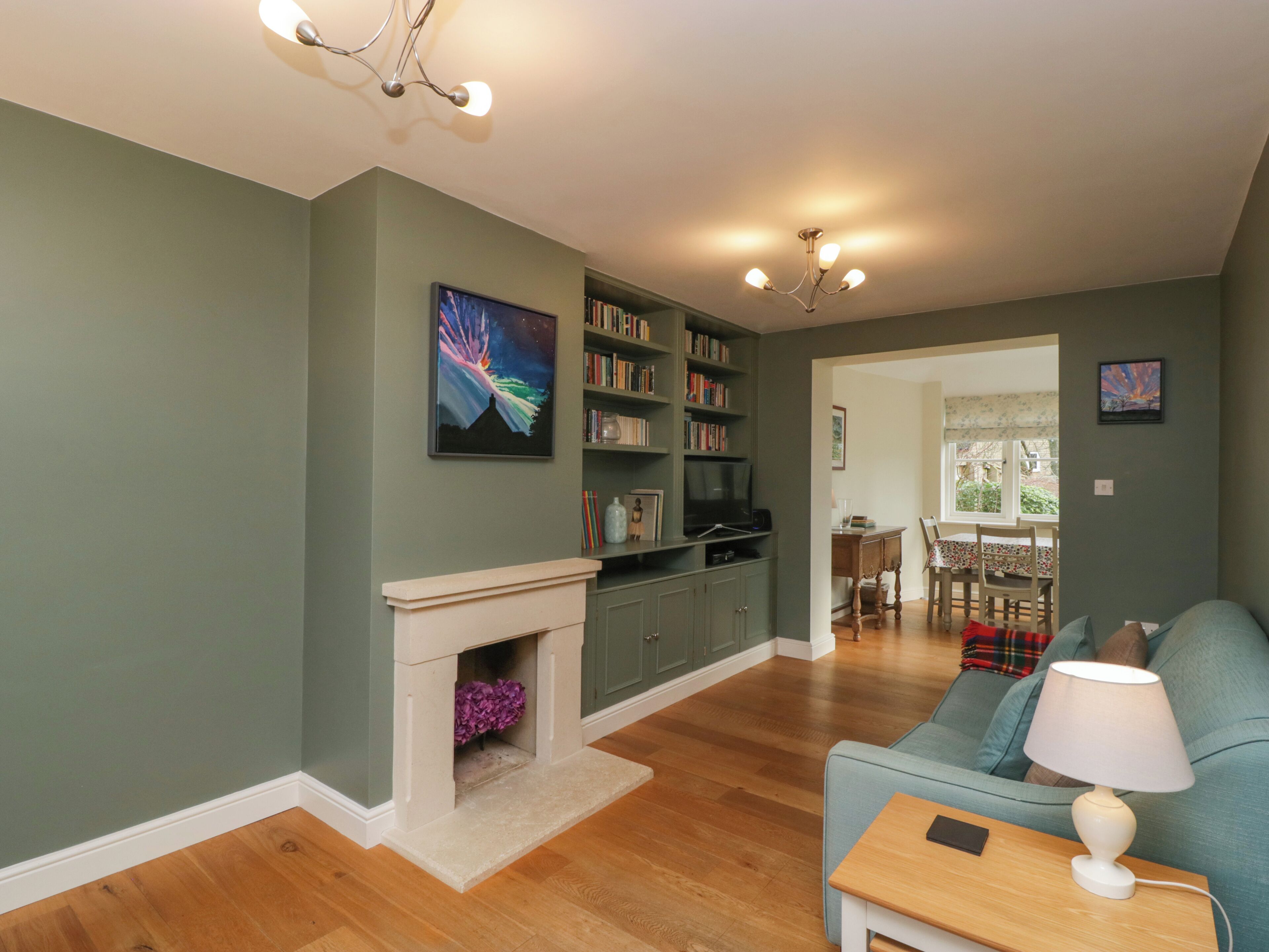 A living room with a fireplace, bookshelves, a sofa, and a dining area with a table and chairs.