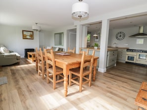 A spacious living area with a wooden dining table and chairs, a sofa, and a kitchen with modern appliances. - West Farm (Great Yarmouth)