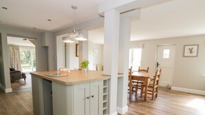 A spacious kitchen with a central island, wooden dining table, and chairs. - West Farm (Great Yarmouth)